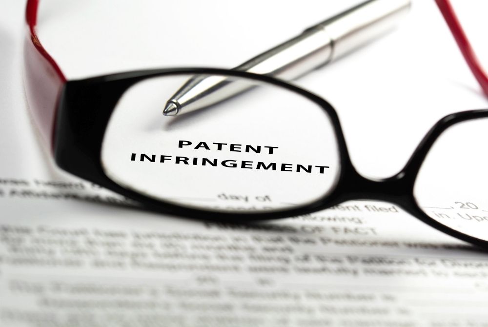 piece of paper that says patent infringement with a pair of glasses